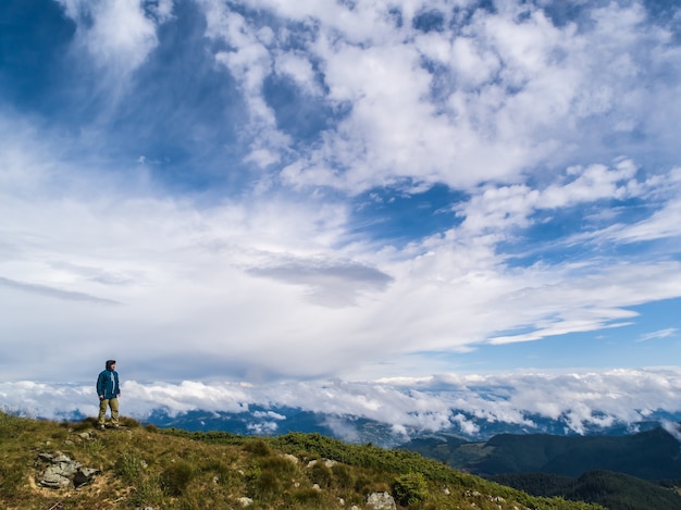 De man die op de rots staat tegen prachtige wolken