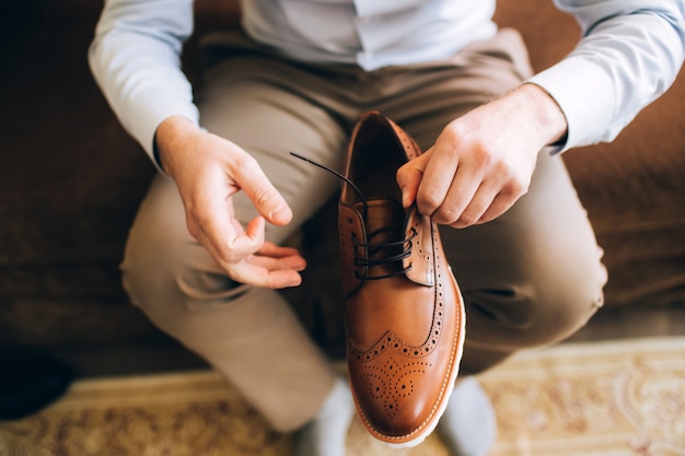 De man draagt schoenen. Bind de veters aan de schoenen. Heren stijl. Beroepen. Ter voorbereiding op het werk, naar de vergadering.