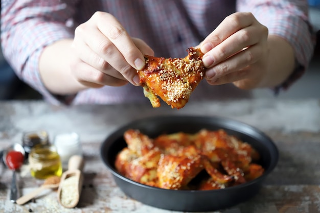 De man eet kippenvleugels. Gebakken kippenvleugels.