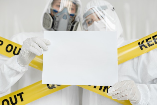 De man en de vrouw van artsenepidemiologen houden wit leeg leeg bord met plaats voor tekstbeeld. Gele lijn Bewaar quarantaine