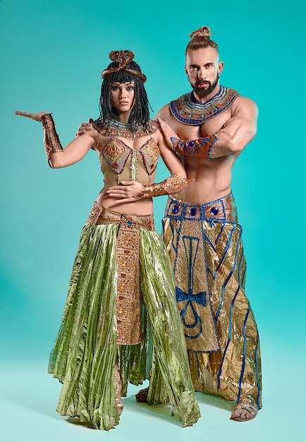 De man en vrouw in de beelden van de Egyptische farao en Cleopatra op blauwe studioachtergrond