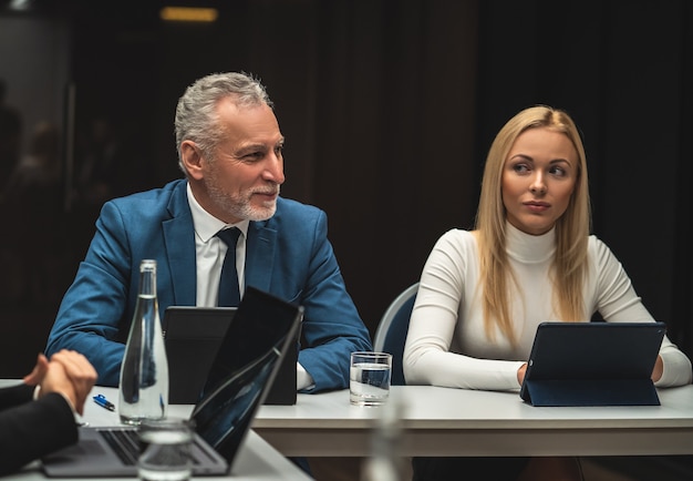 De man en vrouw zitten aan tafel op zakelijke conferentie