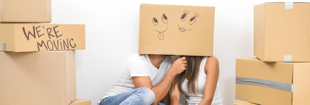 De man en vrouw zitten op de grond met een kartonnen doos op de hoofden