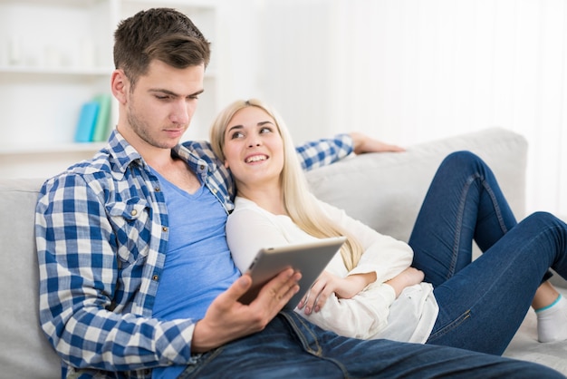 De man houdt de tablet bij de vrouw op een bank