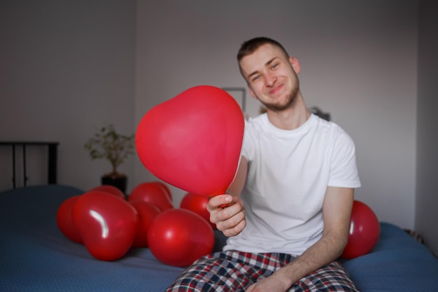 De man houdt een ballon vast in de vorm van een hart voor Valentijnsdag
