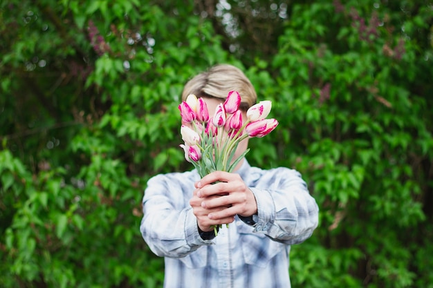 De man houdt een boeket tulpen voor zich vast