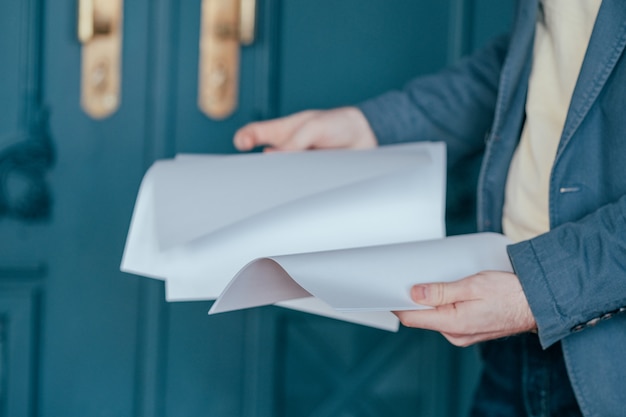 Foto de man in blauw jasje pak met vellen papier in zijn handen, close-up