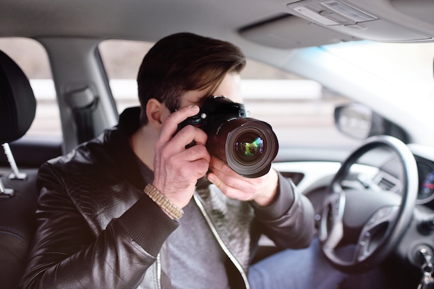 De man in de auto bekijkt de foto's op de camera. spion, paparazzi, journalist, fotograaf.