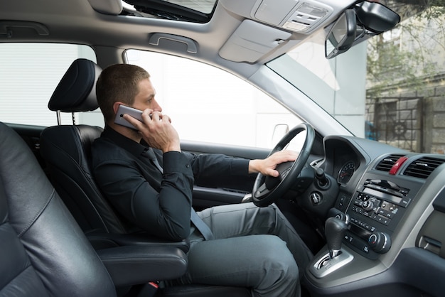 De man in de auto praat aan de telefoon