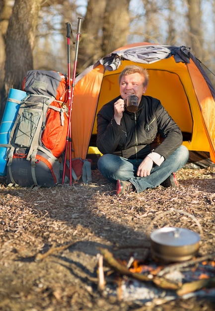 De man in de mars zit bij tent en kampvuur