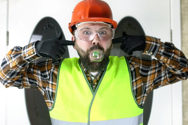 Foto de man in de vorm van een helm en handschoenen, die een gloeilamp vasthoudt