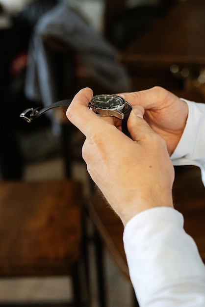 De man in het bruine pak kijkt op zijn horloge, handklok