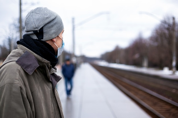 De man in het gasmasker wacht op de trein. Concept: verkoudheid, griep, coronavirus.