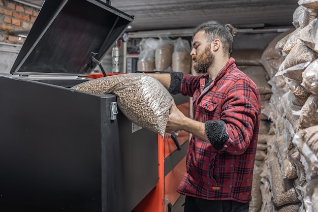 De man laadt de pellets in de vastebrandstofketel en werkt met biobrandstoffen