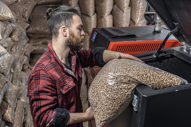 De man laadt de pellets in de vastebrandstofketel en werkt met biobrandstoffen