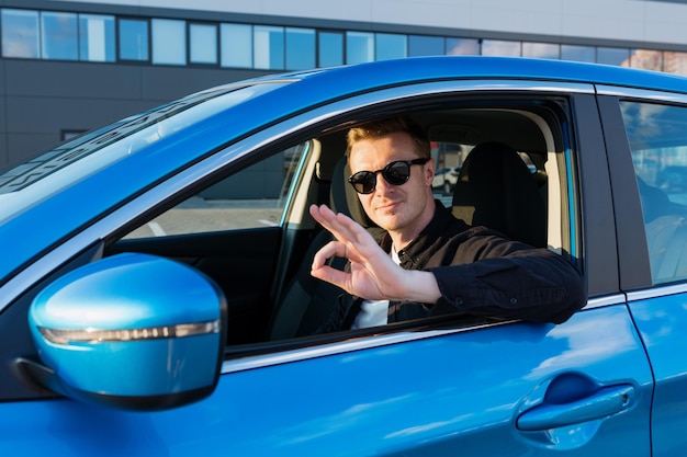 De man laat zien dat de auto cool is zittend in de cabine een auto kopen