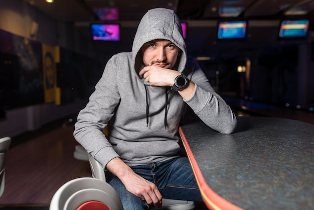 De man met de grijze hoodie zit in een bowlingclub