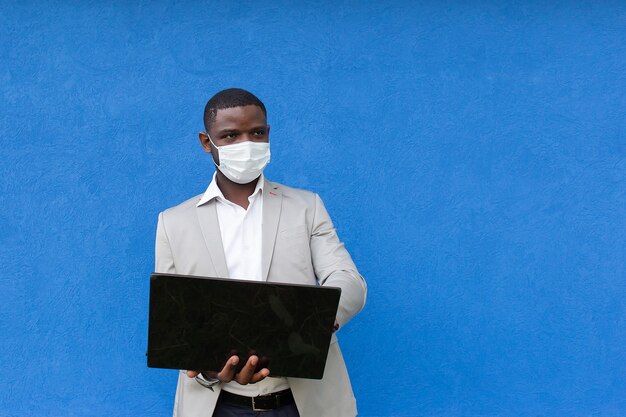 De man met een beschermend masker met een laptop in zijn hand