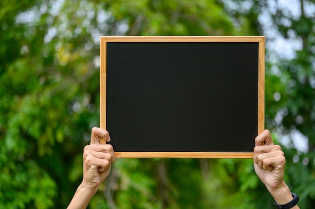 De man met een schoolbord op het buiten veld