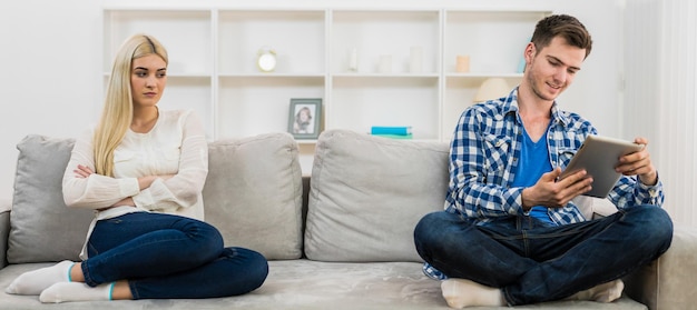 De man met een tablet zit bij een droevige vrouw op de bank