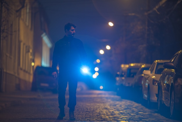 De man met een zaklamp inspecteert de straat. avond nacht tijd