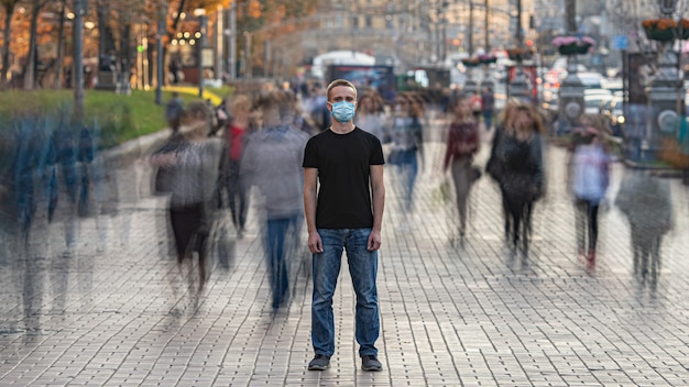 De man met medisch gezichtsmasker staat op de drukke stadsstraat