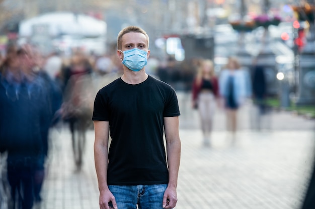 Foto de man met medisch masker op zijn gezicht staat midden in de menselijke stroom