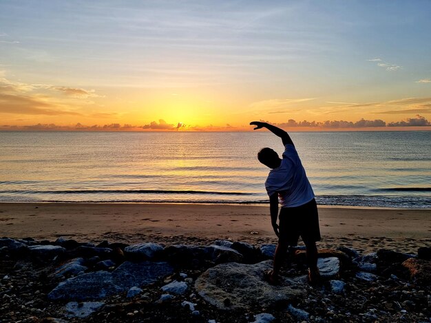 De man oefent op het strand tijdens zonsopgang in de vroege ochtend