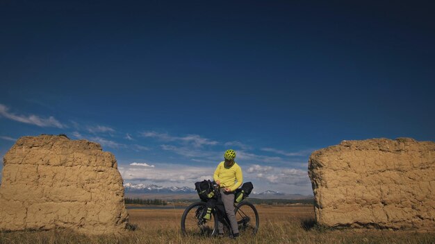 De man reist op gemengd terrein fietstochten met bikepacking De reiziger reis met fietstassen Sport bikepacking fiets sportkleding in groen zwarte kleuren Berg besneeuwde stenen boog