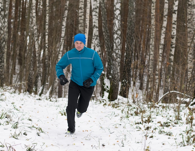 De man rent graag in het winterbos.