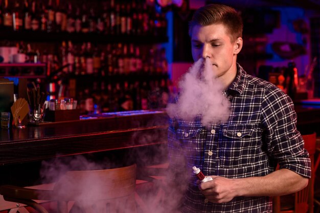 De man rookt een elektronische sigaret bij de vape-winkel. Vape-bar.