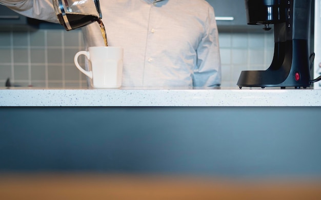 De man schenkt zichzelf een kop koffie.