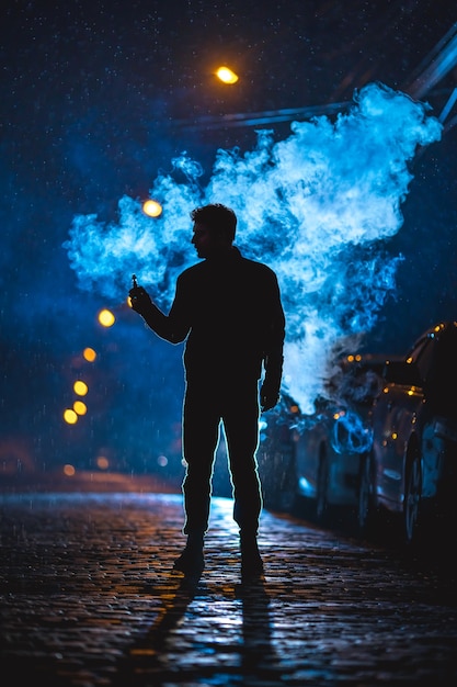 Foto de man staat in de buurt van de rookwolk. avond nacht tijd