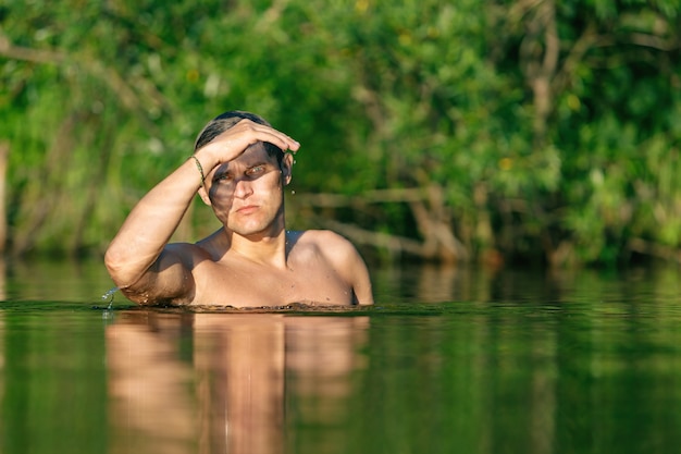 De man stortte zich in het water. De man staat tot aan zijn borst in het water.