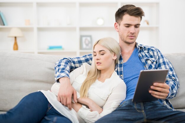 De man zit met een tablet bij de slapende vrouw