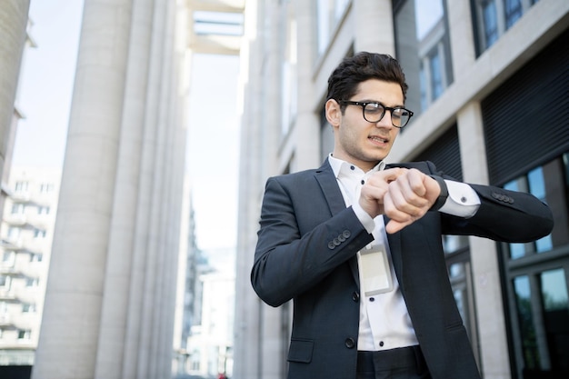 De manager een man met een bril kijkt naar een smartwatch gebruikt een app gaat aan het werk in een nieuw kantoor