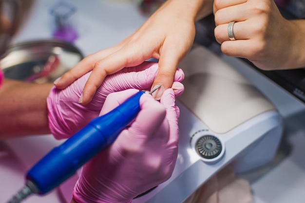 De manicure bedekt haar nagels met nagellak Een vrouw doet een manicure en brengt nagellak aan