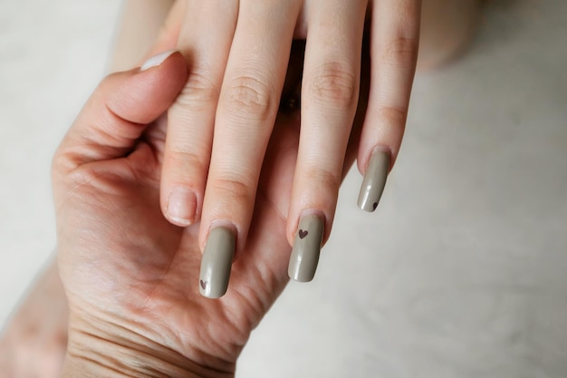 de manicure houdt de hand vast van een cliënt met slordige gebroken nagels met een overwoekerde manicure