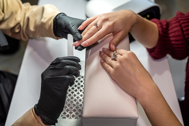 De manicurehandschoenen houden de hand van de klant vast en werken ermee tijdens de epidemie