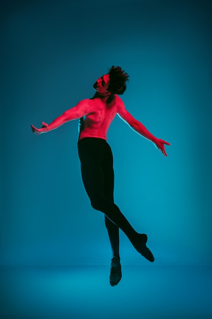 Foto de mannelijke atletische balletdanser die dans uitvoert op levendige blauwe achtergrond. studio opname. modern ballet, eigentijds concept. fitte jongeman. kaukasisch model