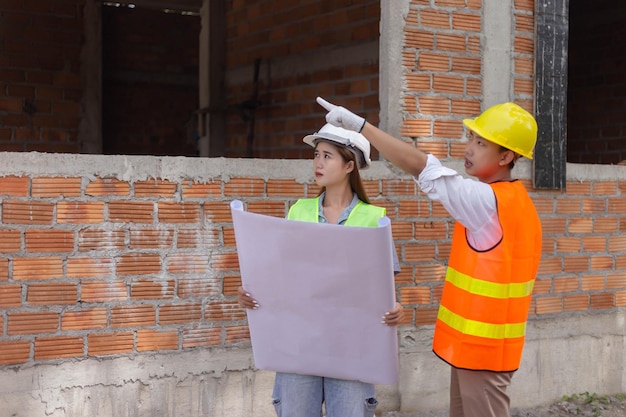 De mannelijke en vrouwelijke technische collega's die kijken en uitzoeken over de bouwconstructie