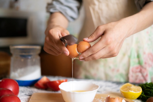 De mannelijke handen van de kokbakker breken ei terwijl voedselvoorbereiding