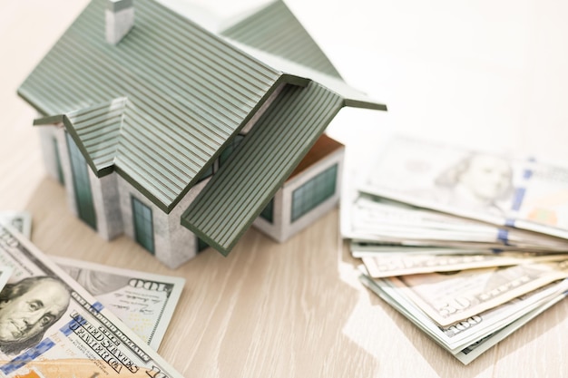 De maquette van het huis kost op een stapel bankbiljetten. Aankoop en verkoop.