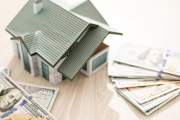 Foto de maquette van het huis kost op een stapel bankbiljetten. aankoop en verkoop.