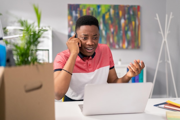 De medewerker van de klantenservice zit op kantoor aan het bureau voor een laptopscherm en praat aan de telefoon