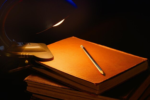 De meegeleverde lamp en een stapel oude boeken op het bureau Onderwijsconcept