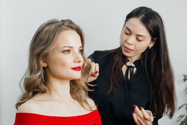 De meester doet een mooie blonde make-up in een schoonheidssalon