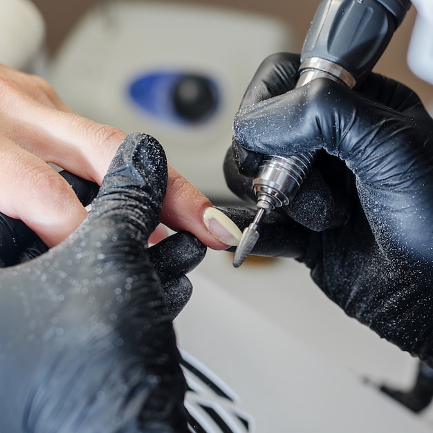 De meester doet hardwaremanicure in de schoonheidssalon