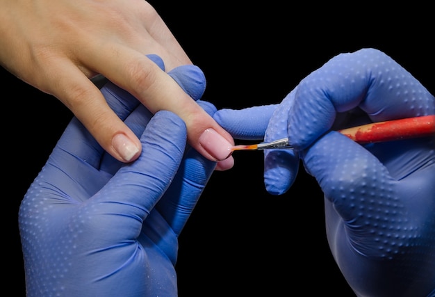 De meester lakt de nagels van de klant close-up