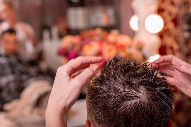 De meester plaatst het haar van een man in een kapperszaak, een kapper maakt een kapsel voor een jonge man